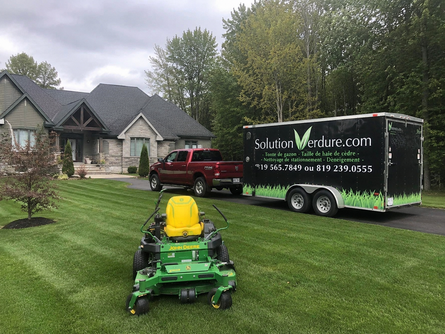 Camion, remorque et tondeuse John Deere de Solution Verdure devant une résidence de Sherbrooke